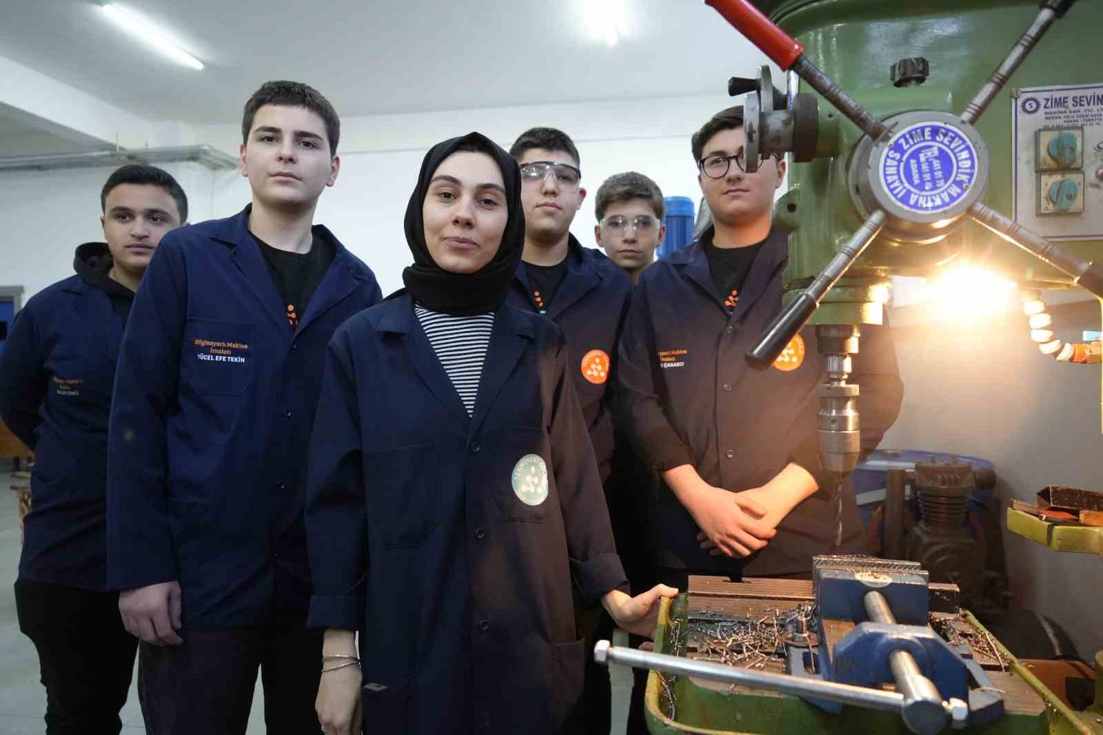 Kadın öğretmen torna tezgahında öğrencilerine üretimi öğretiyor
