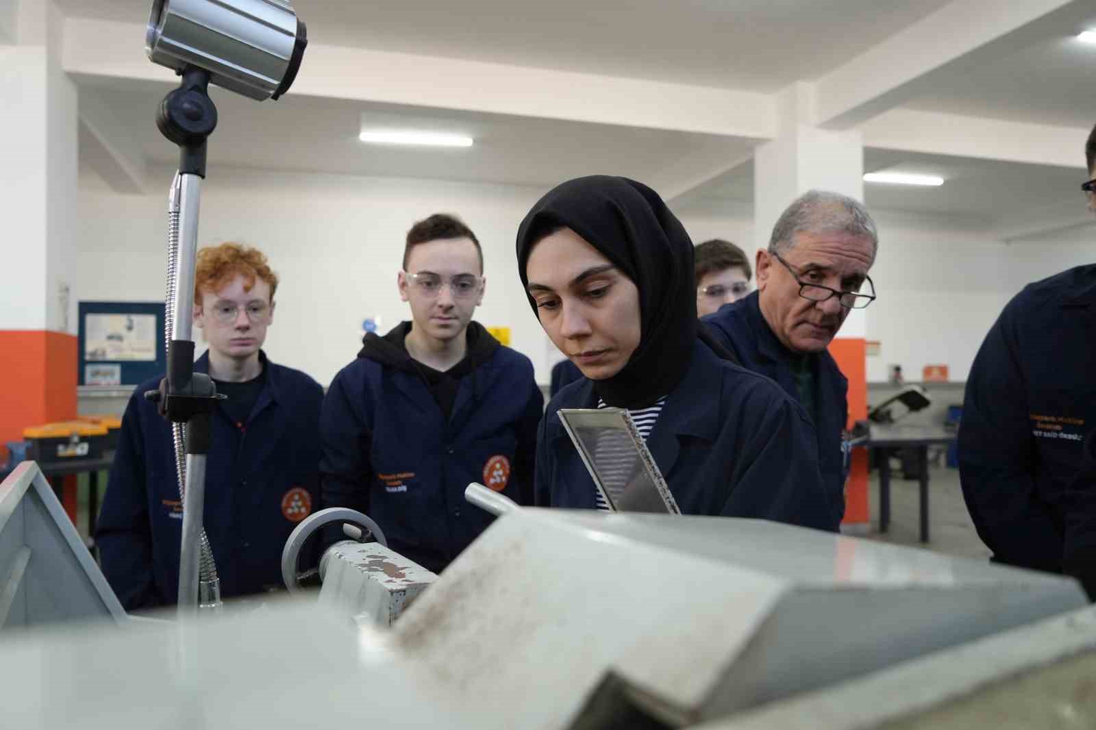 Kadın öğretmen torna tezgahında öğrencilerine üretimi öğretiyor
