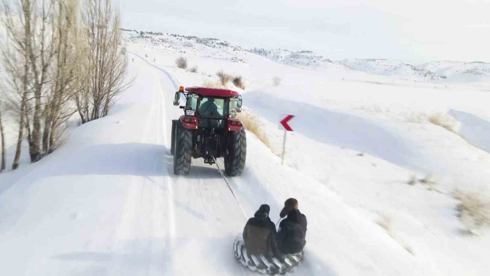 Kar yağışını fırsata çevirdiler, traktörün arkasında kayarak eğlendiler
